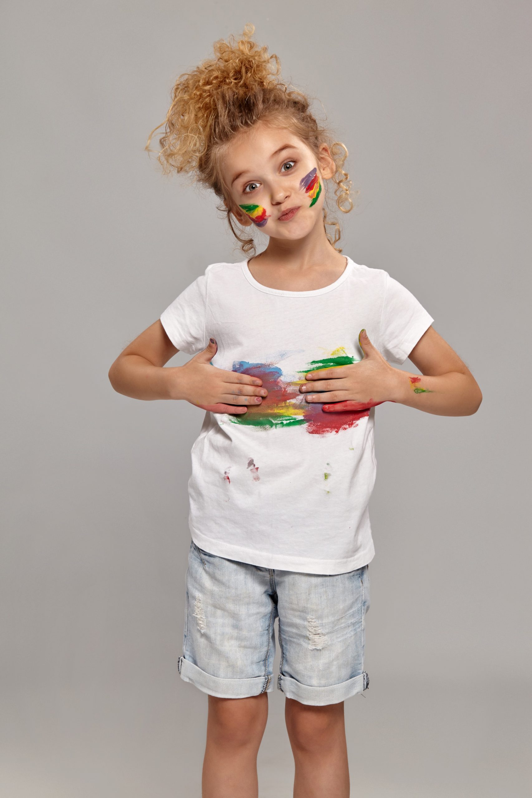 Child joyfully painting with colorful face paint, representing creative sport discovery.